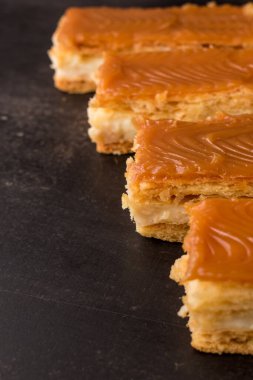 Siyah ahşap masada kremalı karamel soslu atıştırmalıklar.