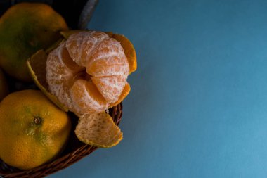 Fotokopi alanı olan mavi bir yüzeyde sepette taze mandalinalar.