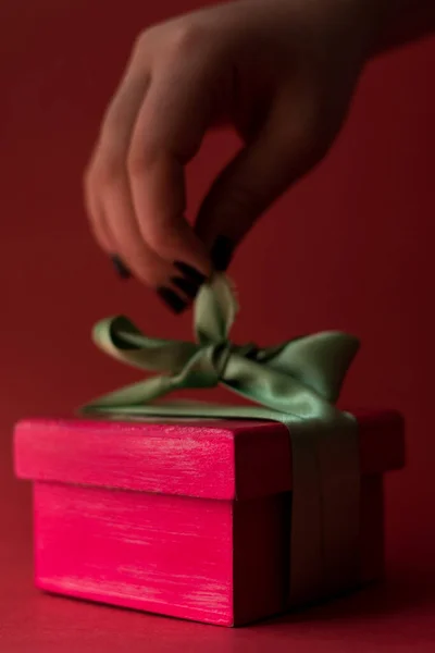 Kinyitni Egy Rózsaszín Ajándékdobozt Zöld Szalaggal Egy Piros Felületen — Stock Fotó