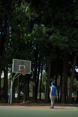 Mavi kolsuz tişört giyen ve basketbol sahasında basketbol oynayan bir adam.