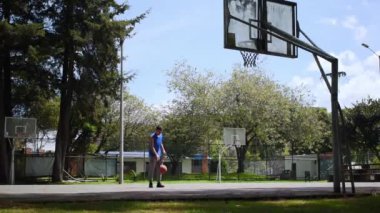 Mavi kolsuz tişört giyen ve basketbol sahasında basketbol oynayan bir adam.