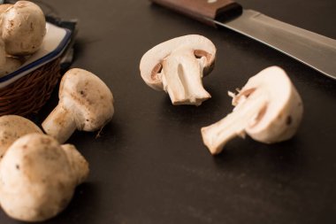 Şampiyon ve mantarı siyah tahta bir masada bıçakla sepete koy. 