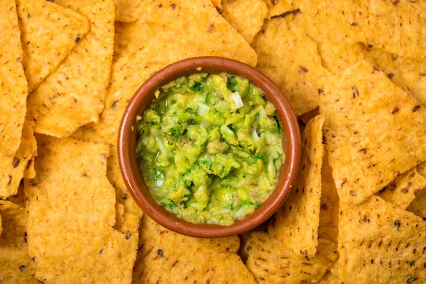 Tencerede kızarmış nachos ve yeşil bir yüzey üzerinde taze guacamole. 