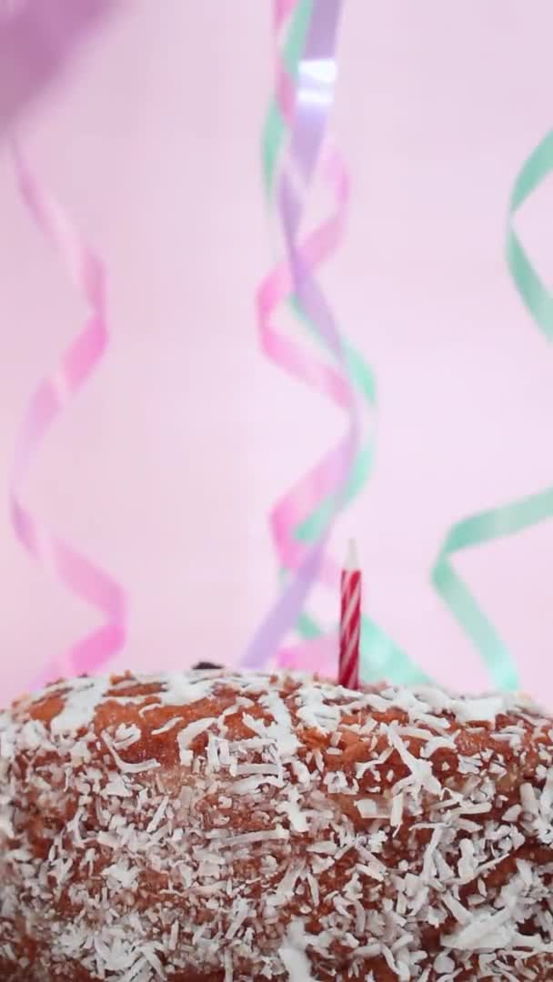 一个高加索人的手把一些生日蜡烛埋在蛋糕里和一些粉色背景的生日礼物的垂直视频 — 图库视频影像