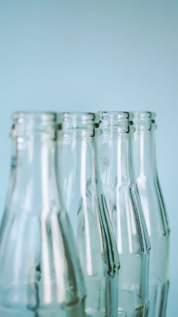 明るい青色の背景を持ついくつかのガラス瓶を照明 — ストック動画
