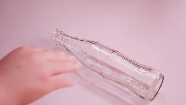 Girl Hand Spinning Glass Bottle Pink Surface — Video