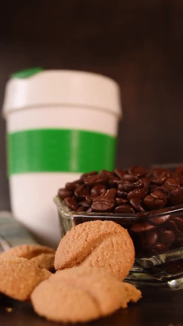 黒を背景に手で取られた熱い飲み物のためのコーヒー豆 クッキー プラスチック製の魔法瓶の垂直ビデオ — ストック動画