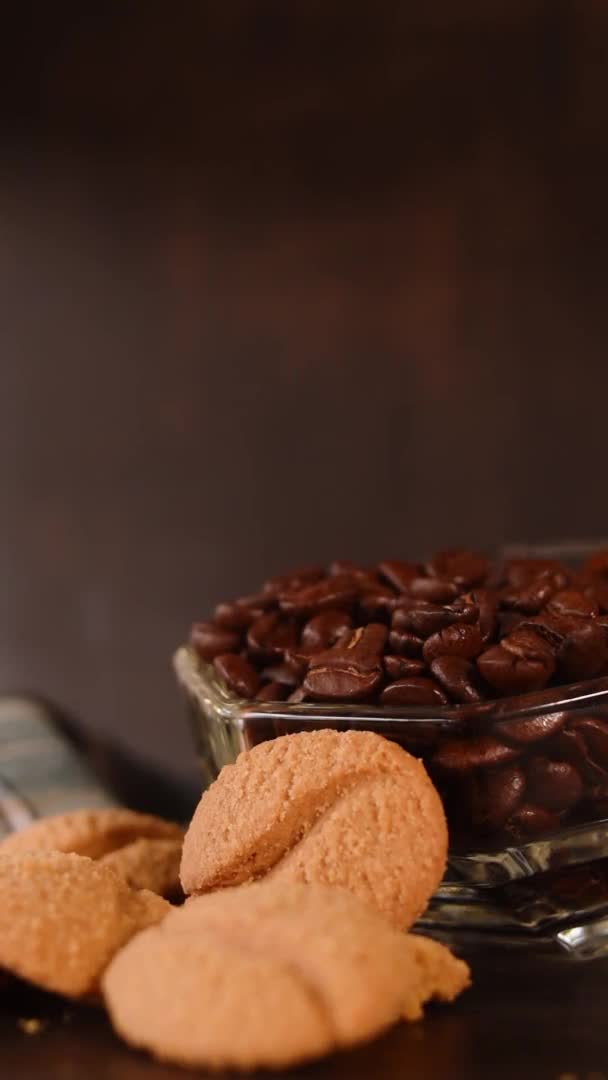 黒を背景に手が残した熱い飲み物のためのコーヒー豆 クッキー プラスチック製の魔法瓶の垂直ビデオ — ストック動画