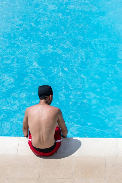 Man Wearing Red Shorts Sitting Edge Blue Pool Sunny Day — Stock Photo, Image