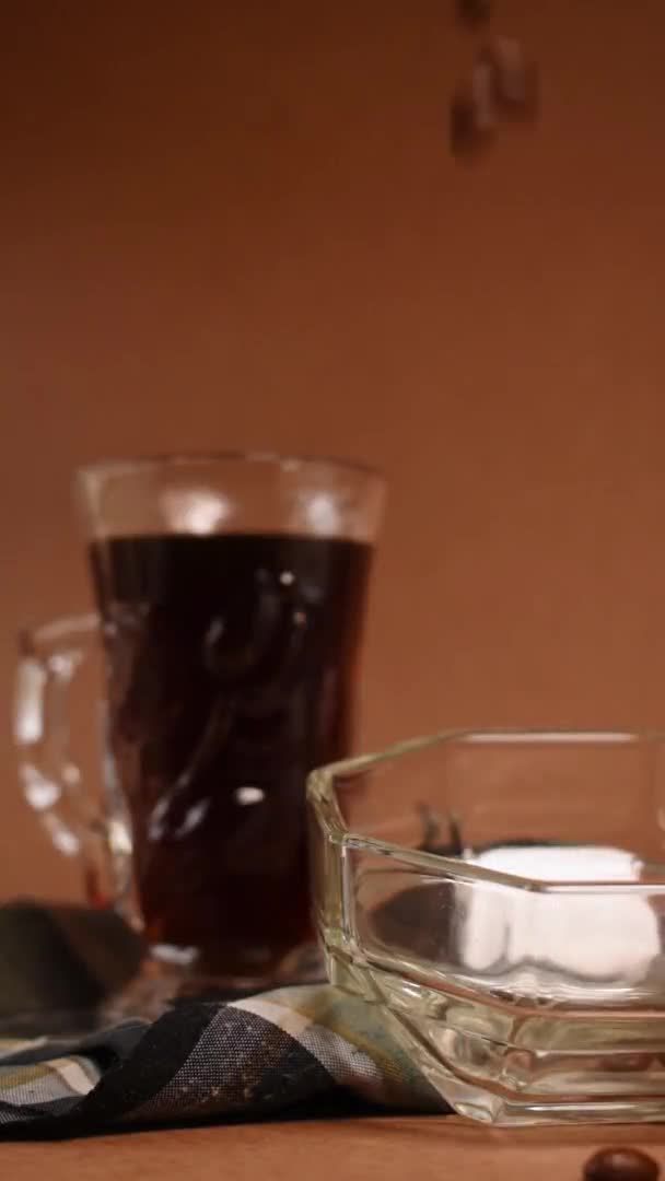 Несколько Черных Кофейных Зерен Выходящих Стакана Рядом Чашкой Черного Кофе — стоковое видео