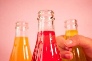 Pembe arka planda renkli soğuk soda şişeleri.