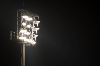 Karanlık bir gecede stadyumun ışığı açık.