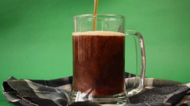 Yeşil arka planda bir bardak siyah soğuk bira dolduruyorum.