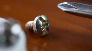 Macro of a little screw being taken by a ghand on a wooden table 