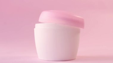 Eller pembe arka plandaki kadınlar için cilt kremi şişesi açıyor