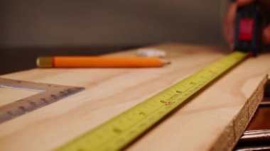 Carpenter taking wooden table measurements with some tools