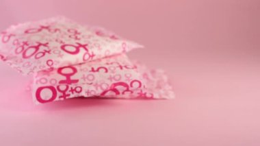Hand putting a sanitary napkin with women symbol on pink background