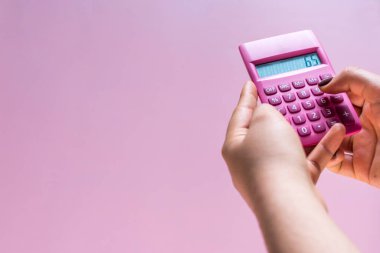 Hands using a pink calculator with white numbers on a pink surface