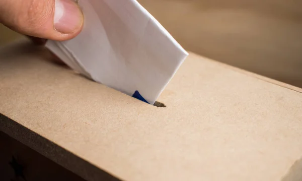 Hand casting vote in a wooden box