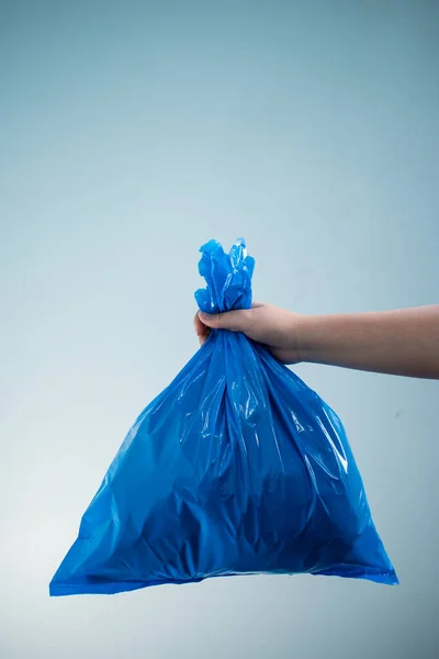 Hand holding a recycle blue plastic bag on blue background