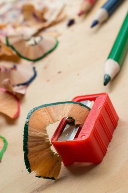 Plastik kalem açacağı ve ahşap bir masada renkli kalemler.