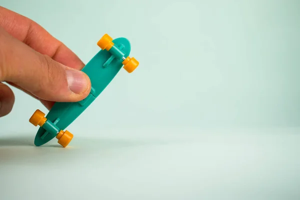 Yeşil arka planda kaykay tutan parmaklar