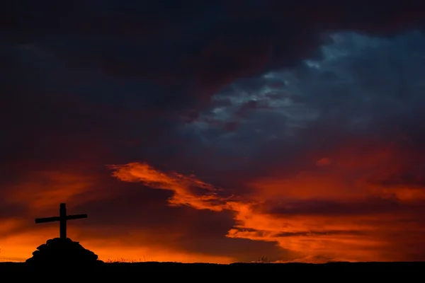 La silueta de la cruz de madera y el cielo ardiente en el fondo — Foto de Stock