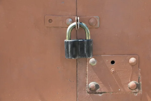 Vieux cadenas noir sur une porte de garage en métal rouge — Photo