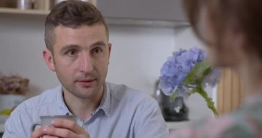 Sevgili karısını dikkatle dinleyen ve kahvaltıda ellerini öpen bir adamın yakın çekimi.