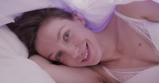 Hermosa mujer en lencería blanca seductora con hermosos ojos azules esperando a su marido en la cama. Sensual escena sexy — Vídeo de stock