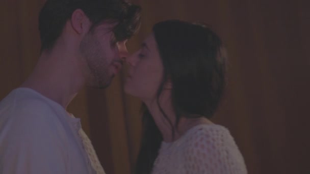 Apasionado beso de una joven pareja en el dormitorio por la noche — Vídeos de Stock
