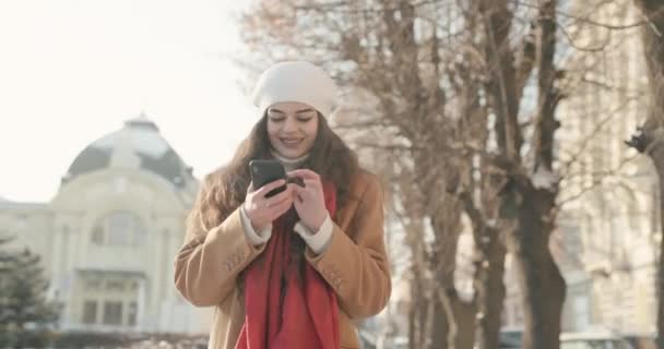 Schönes hübsches Mädchen, das durch die Innenstadt läuft und mit Freunden in sozialen Netzwerken chattet — Stockvideo