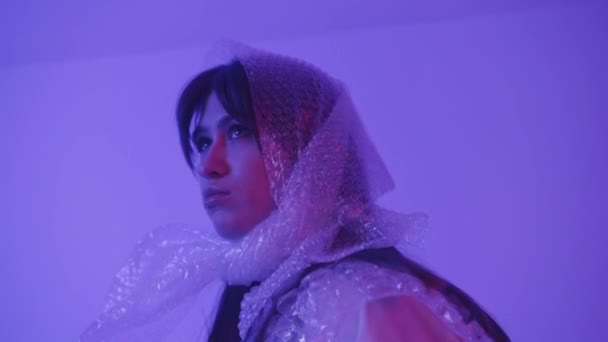 Mode meisje in polyethyleen. Mode met polyethyleen. Meisje draagt een plastic sjaal op haar hoofd. — Stockvideo