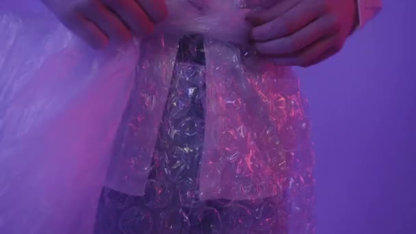人々はピンクの光のプリズムを通してプラスチックを使用します。ポリエチレンは女の子に身に着けている. — ストック動画