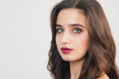 Parlak makyajlı ve saç şekilli genç bir kız. Direk kameraya bak. Doğal makyaj. Parlak yeşil gözler.