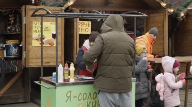 Chernivtsi, Ukrayna-23.12.2019. Genç bir kadın, karsız bir kış gününde Yeni Yıl Fuarı 'nda müşterilerine kahve yapıyor.