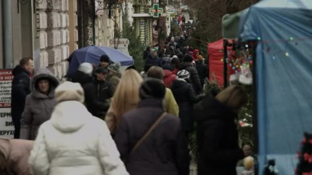 Chernivtsi, Ukrayna - 23.12.2019. Kalabalıktaki insanlar Noel süslerini ve Noel ağaçlarını seçmek için acele ediyorlar. — Stok video