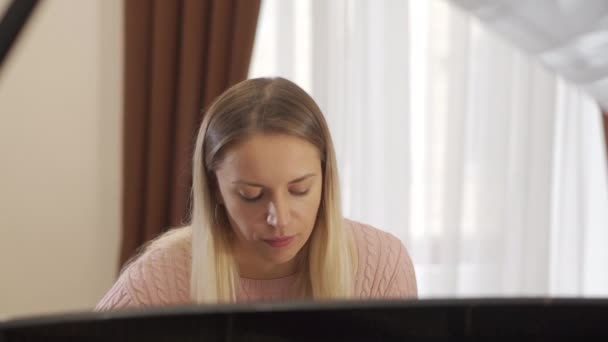 Retrato de una chica atractiva que está encantada con la interpretación de su composición favorita en el piano — Vídeos de Stock