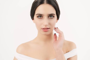 Model doğrudan kameraya bakar, elini yüzüne tutar. Kendinle uyum sağla. Doğal görünüşlü genç bir kız..