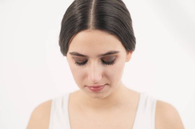 Kız yüzü yakın çekim. Kirpikleri rimel ile kaplanır. Beyaz arkaplan.