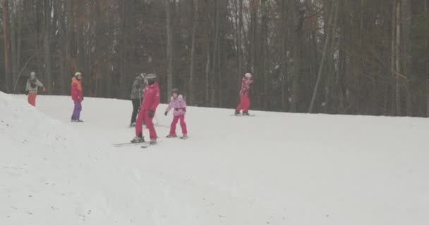 Bukovel, Ucrania - 25 de diciembre de 2020: Trainer enseña a las niñas a esquiar. la gente va a esquiar en la temporada de invierno. — Vídeo de stock