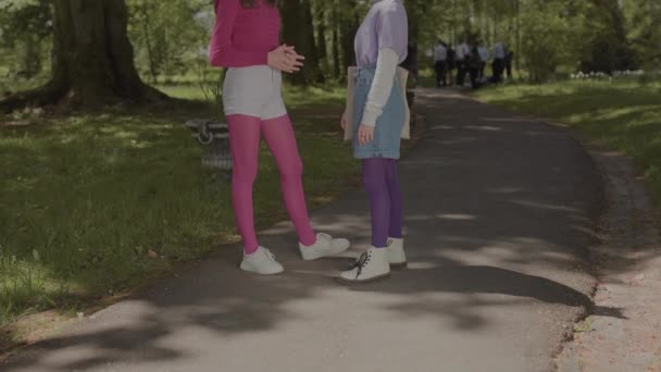 Яркие изображения для девочек на лето. Девушки в стильной одежде разговаривают в парке. — стоковое видео