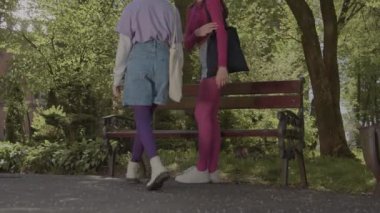 Kız arkadaşlar bahçede bir bankta oturur ve telefonda video izlerler..