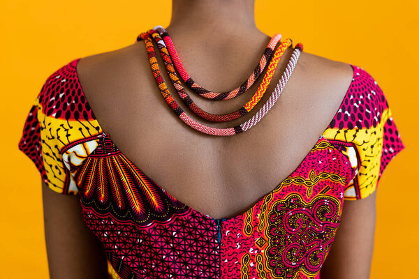 A red necklace on black leather, and a red traditional t-shirt. Details of African style on a bright background.