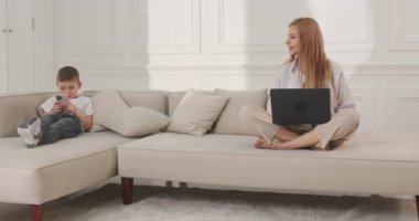 Annesi bilgisayarla uğraşırken çocuk annesinin telefonunda oturuyor. Telefona bağımlılık.