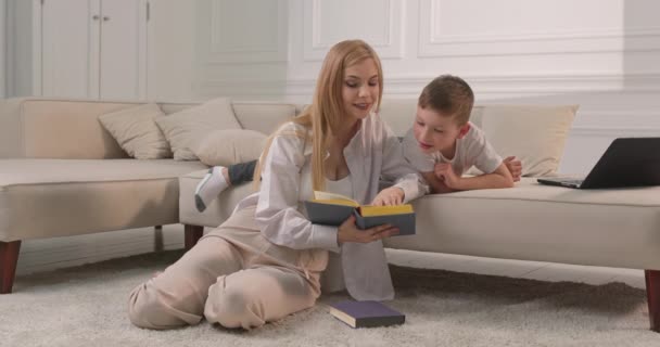 Anne oğluna bir peri masalı okuyor. Kitaptaki çocuklar için eğitici hikayeler.. — Stok video