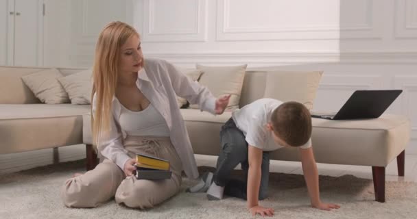Mãe e filho estão se preparando para ler um livro juntos. A criança imita as ações da mãe. — Vídeo de Stock