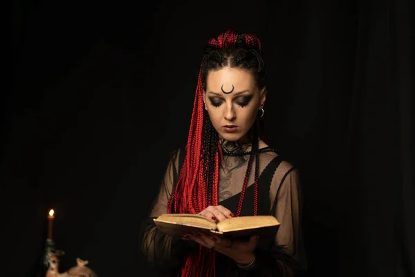 Una bruja que lee nuevos métodos de brujería en el libro. Magia negra. — Foto de Stock