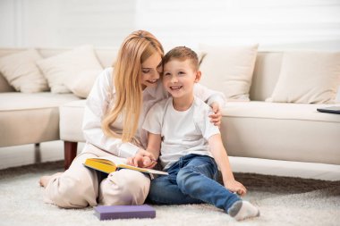 Anne ve oğlu yerde oturup kitap okuyorlar. Faydalı olarak harcanan zaman.