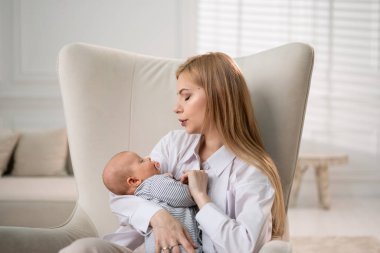 Annem bebeği kollarına aldı ve bir sandalyeye oturdu..